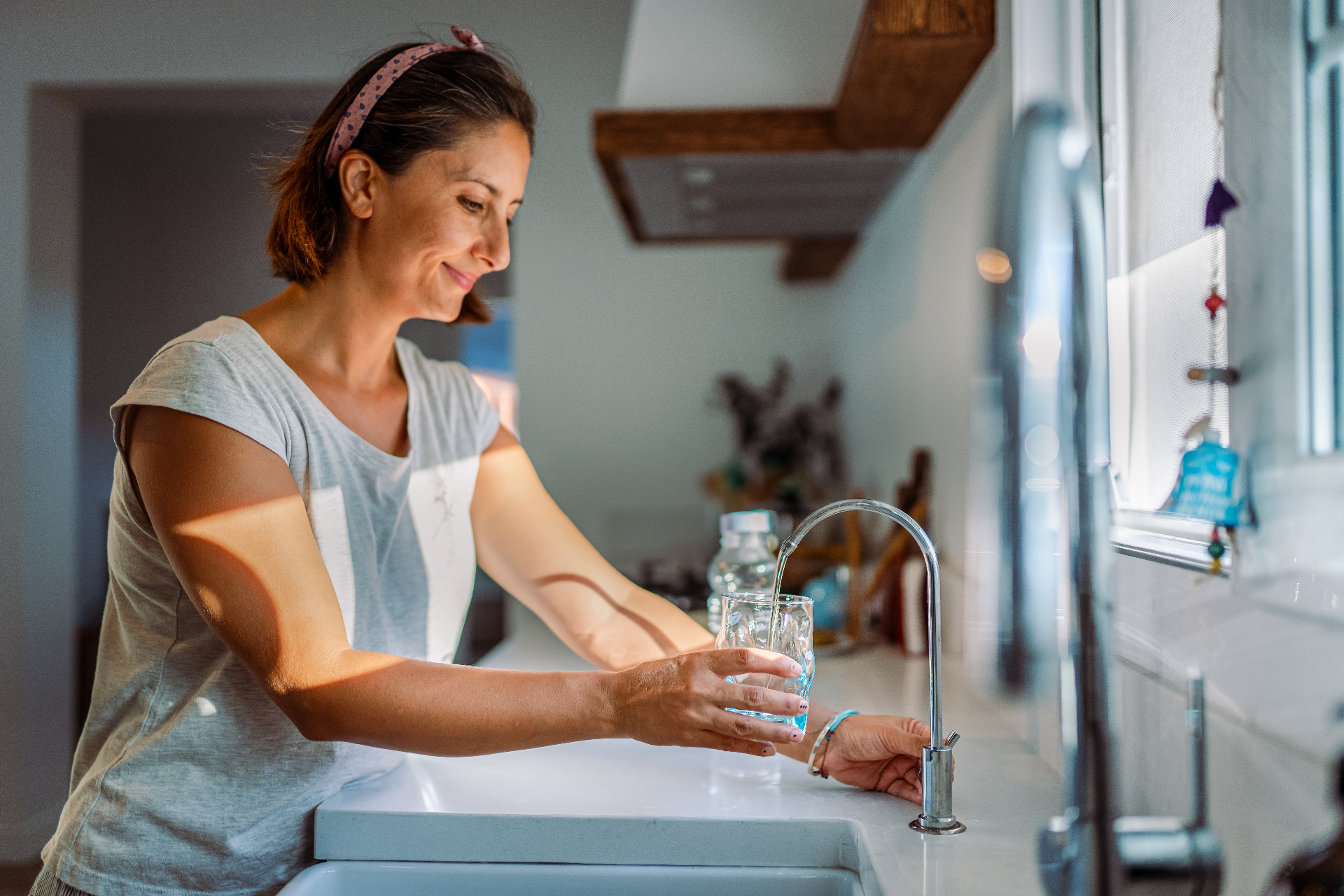 Woman filling a glass at her reverse osmosis kitchen faucet