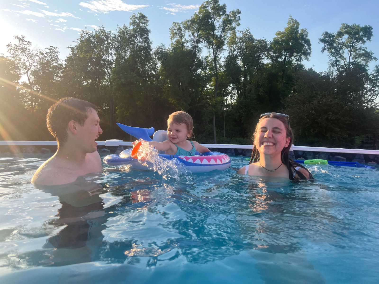 Family with a baby enjoying a sunlit backyard pool