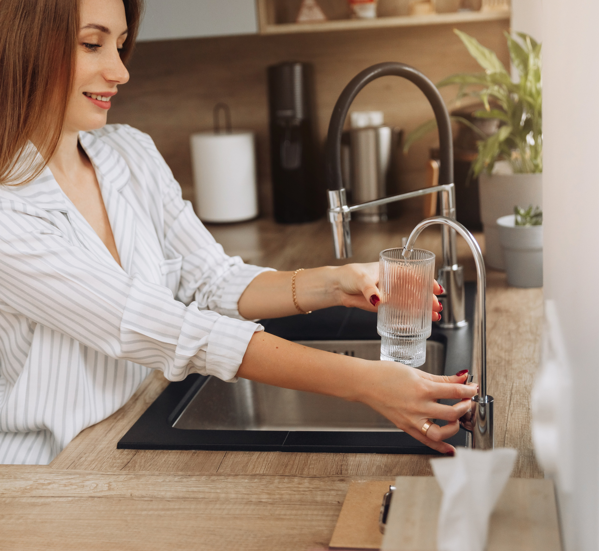 Woman filling a glass with pure water from a kitchen reverse osmosis faucet